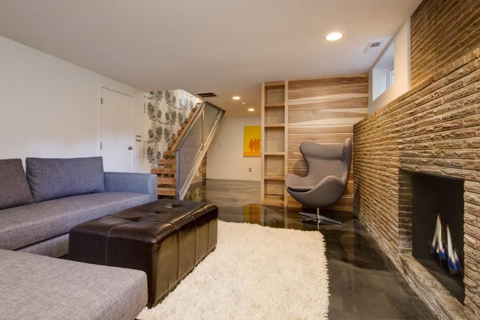 Basement living area with a stone fireplace, wood accent wall and a rounded egg chair